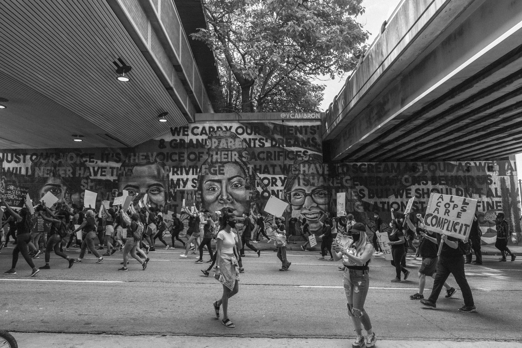 protestors march past mural