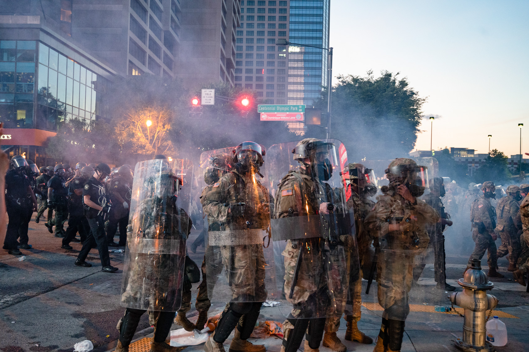 four national guard members with riot shields raised and gas masks on
