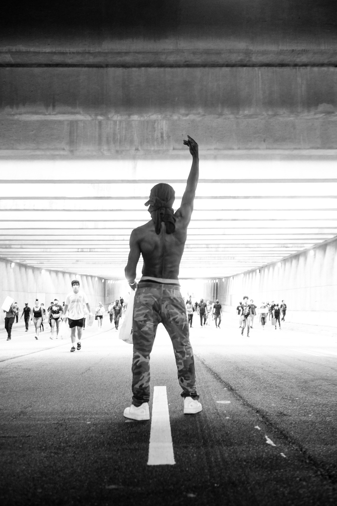 male protestor stands in tunnel with hand raised