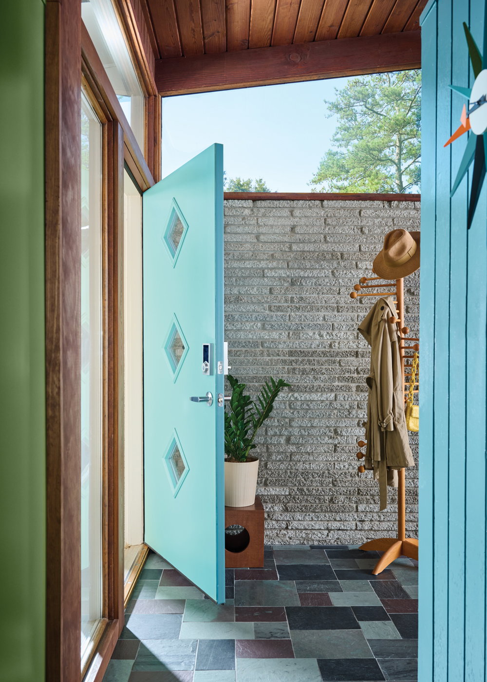 The new turquoise front door has diamond windows as a geometric detail. “We also replaced the outdated tile in the entry with natural slate meticulously laid out by our designers,” says Micaela Quinton of Copper Sky Design & Remodel. “Having slate tile in the foyer is a common feature of MCM homes, so this design brought the home back to its roots.”