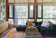A midcentury-meets-industrial duplex in Lake Claire gets a colorful facelift In the family room, a low-slung sofa doesn’t hinder the view of the wooded ravine outside the windows. The rich teal color of the sofa and vibrant rainbow rug embrace the young family’s love of color. Designer Jessica Davis showcased their art collection by creating a gallery wall around the TV.