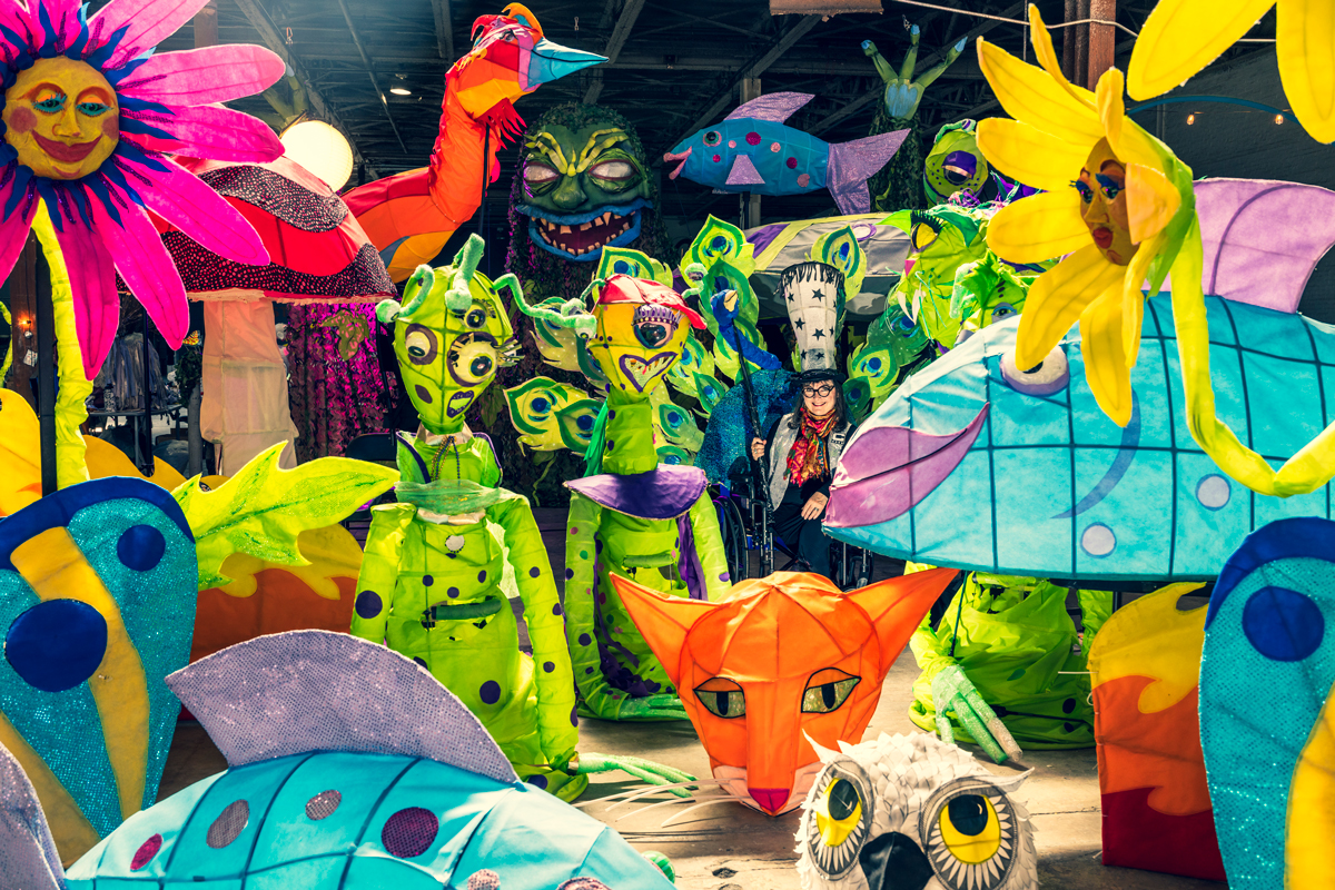 Chantelle Rytter in a warehouse surrounded by monster lanterns, flower lanterns, fish lanterns, and more—all of bright, vibrant colors
