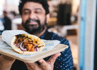 5 Atlanta sister restaurants with lower price points A man smiling in the background while he holds a hot buttered naan wrap