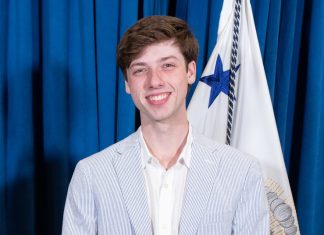 Parker Short smiling while wearing a blue pinstripe suit