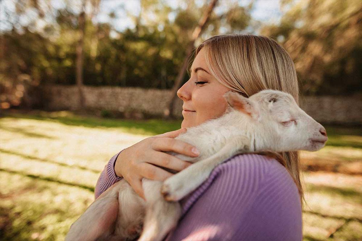 a woman holds a baby sheep in her arms