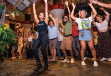 Salsa dancing is taking over metro Atlanta a group of people dancing with their arms up in the air at Ponce City Market