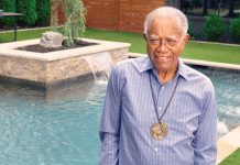 J.T. Johnson smiles in a yard with manicured greenery and a pool behind him