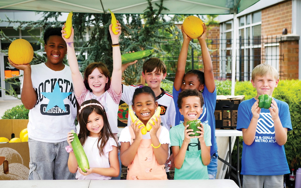 8 kids smile and pose while holding vegetables and helping their community