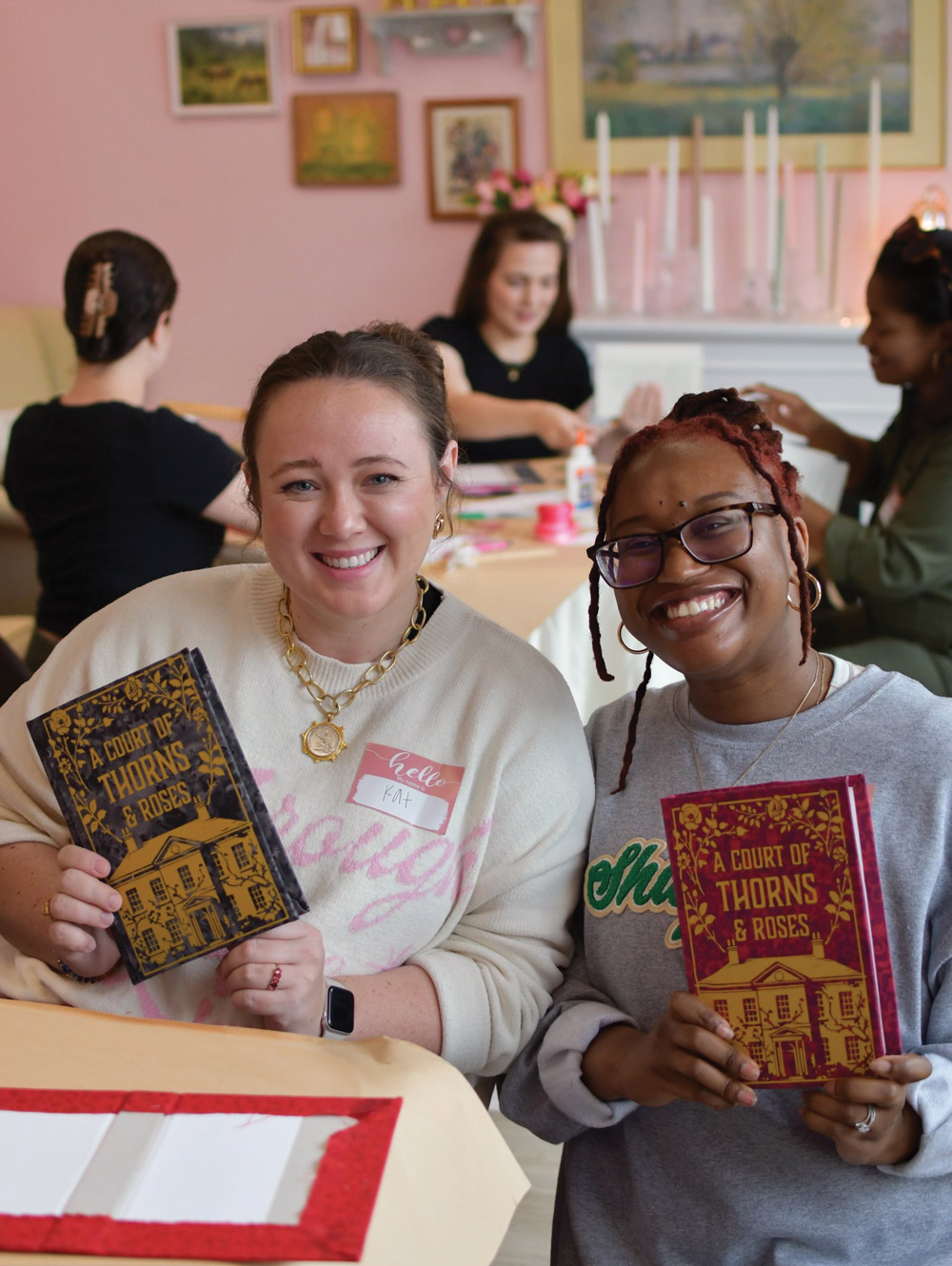 two women smile while holding the book 