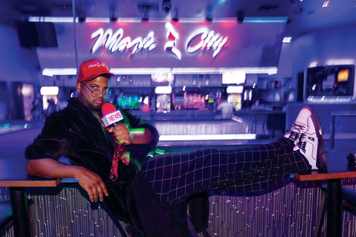 Carldez Goodley (Hood Anchor Ye), holds a mic and looks into the camera at Magic City