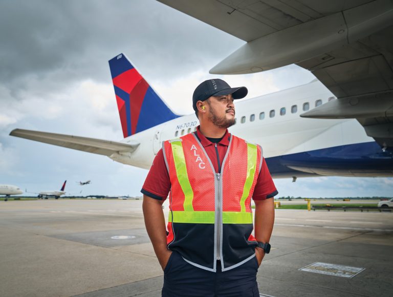 Ryan Vizcarra stands outside, at the tarmac with a Delta plane behind him