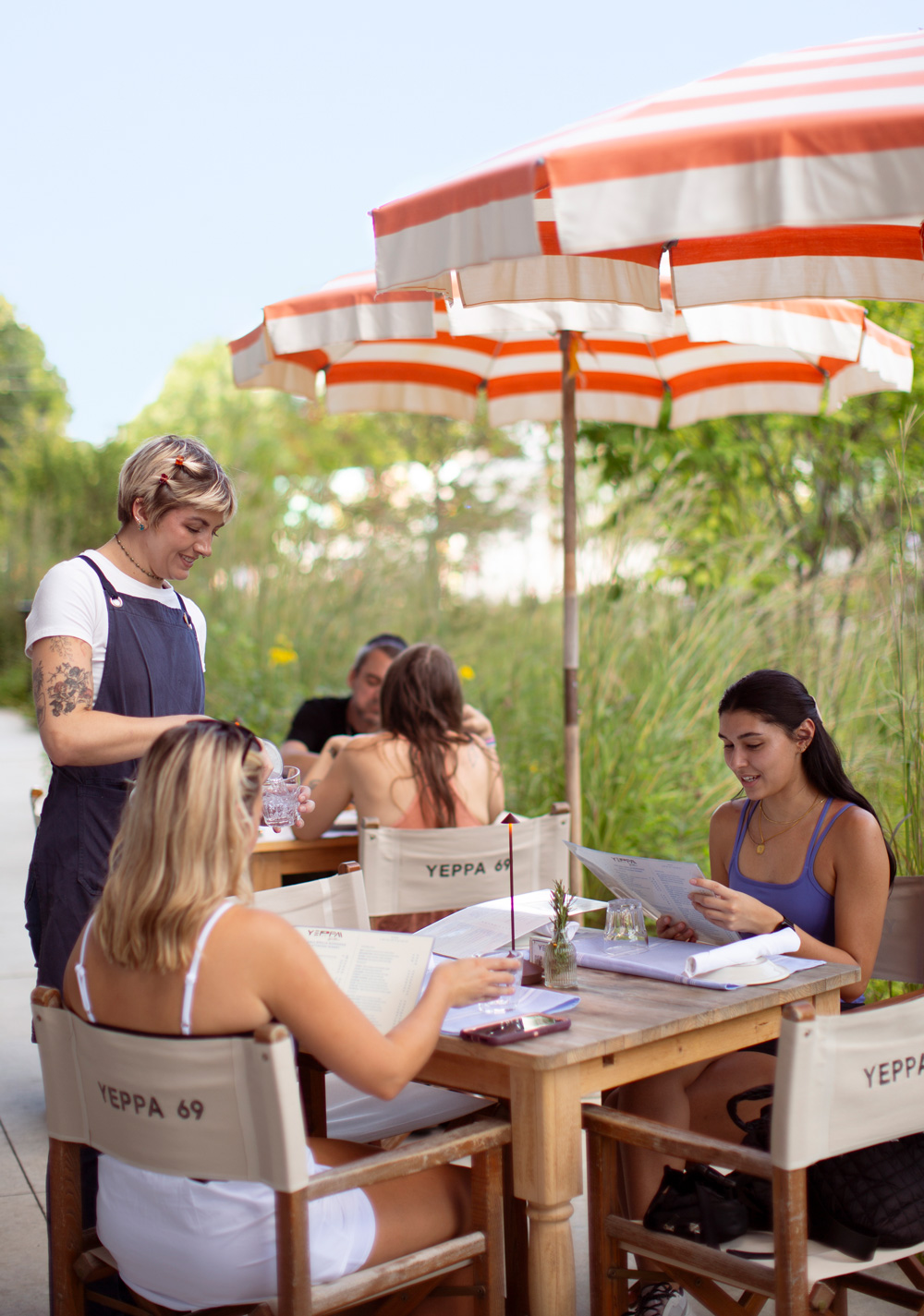 Some people enjoy the patio seating under orange and white striped umbrellas
