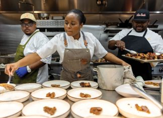 Chryss Lewis plates chicken on more than 10 bowls while chef Robert Butts watches