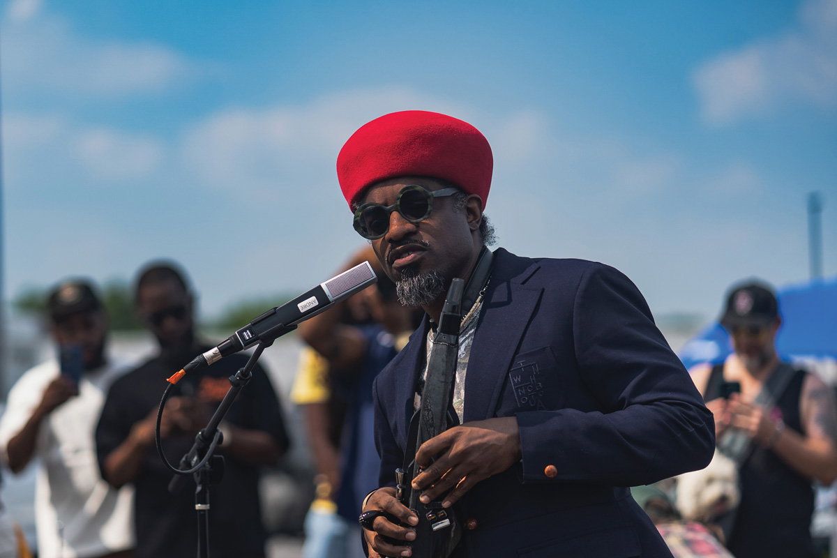 Andre 3000 with a red hat, speaking into a mic