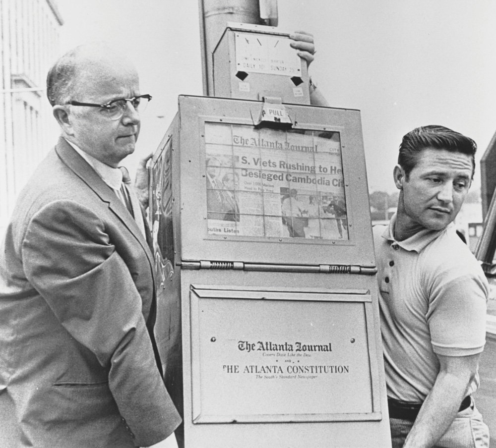 Governor Lester Maddox (left) removes a newspaper vending machine from the Georgia State Capitol in May 1970, after he banner sales of both papers there.