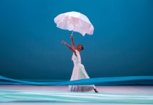 Revelations still moves audiences 50 years after its Atlanta debut a dancer holds a white umbrella in with a blue backdrop behind her and two different shades of blue fabric in front of her