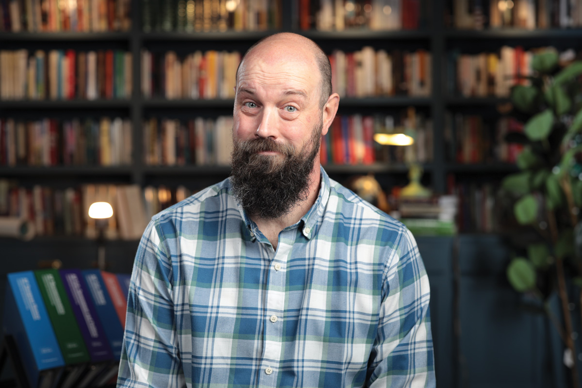 a photo of Steve Heimler wearing a blue and white plaid shirt, sitting in the space where he usually records his youtube videos