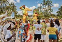a group of people with colorful attire dance at the parade