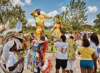 a group of people with colorful attire dance at the parade