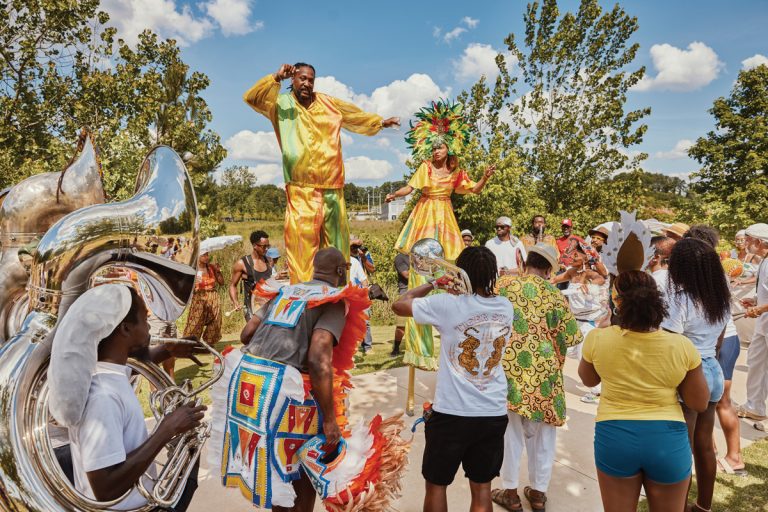 a group of people with colorful attire dance at the parade