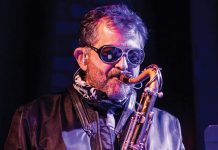 Vinnie Dagostino wears sunglasses while playing the saxophone