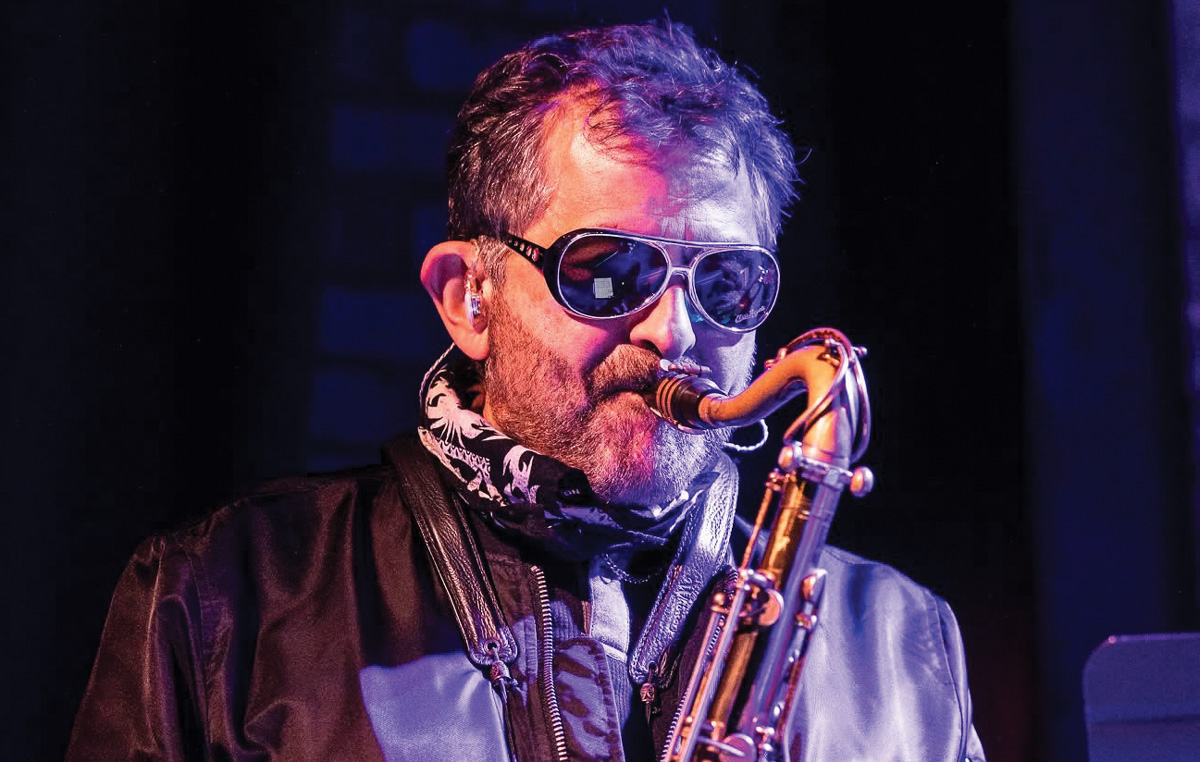 Vinnie Dagostino wears sunglasses while playing the saxophone