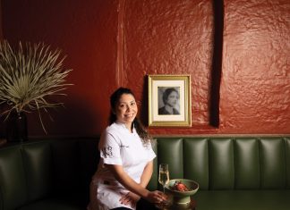 pastry chef Claudia Martinez smiles while sitting iat Bar Ana's green seating booths