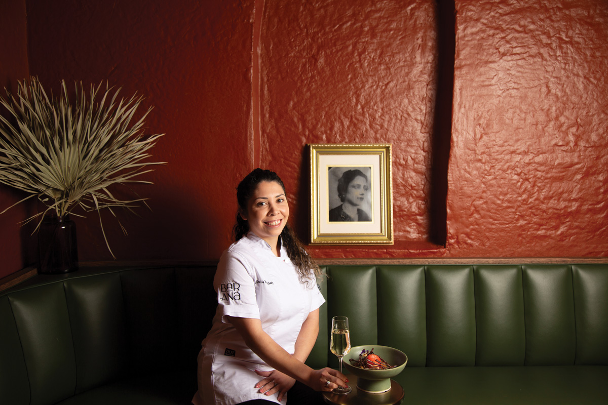 pastry chef Claudia Martinez smiles while sitting iat Bar Ana's green seating booths