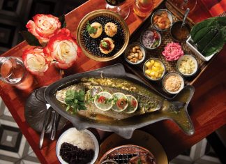 A spread of the whole branzino and the colorful components, including wrapping leaves of miang kham