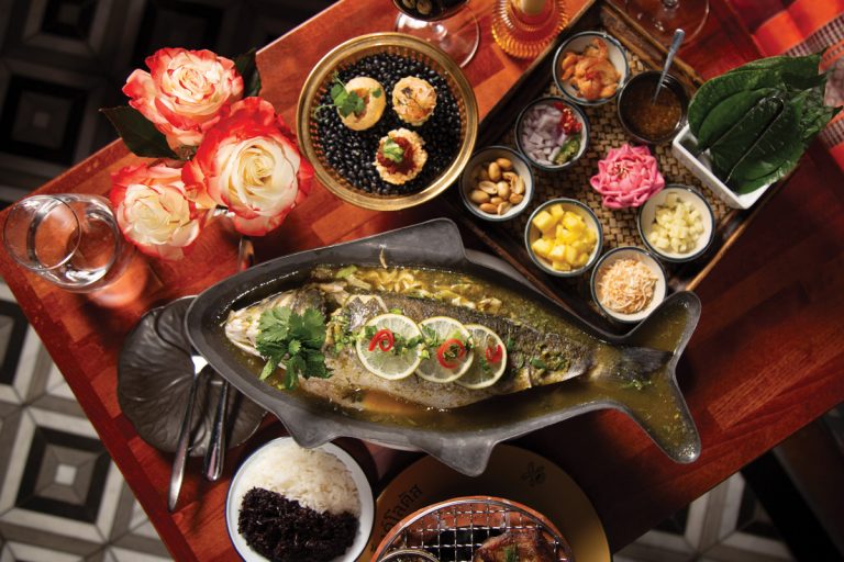 A spread of the whole branzino and the colorful components, including wrapping leaves of miang kham
