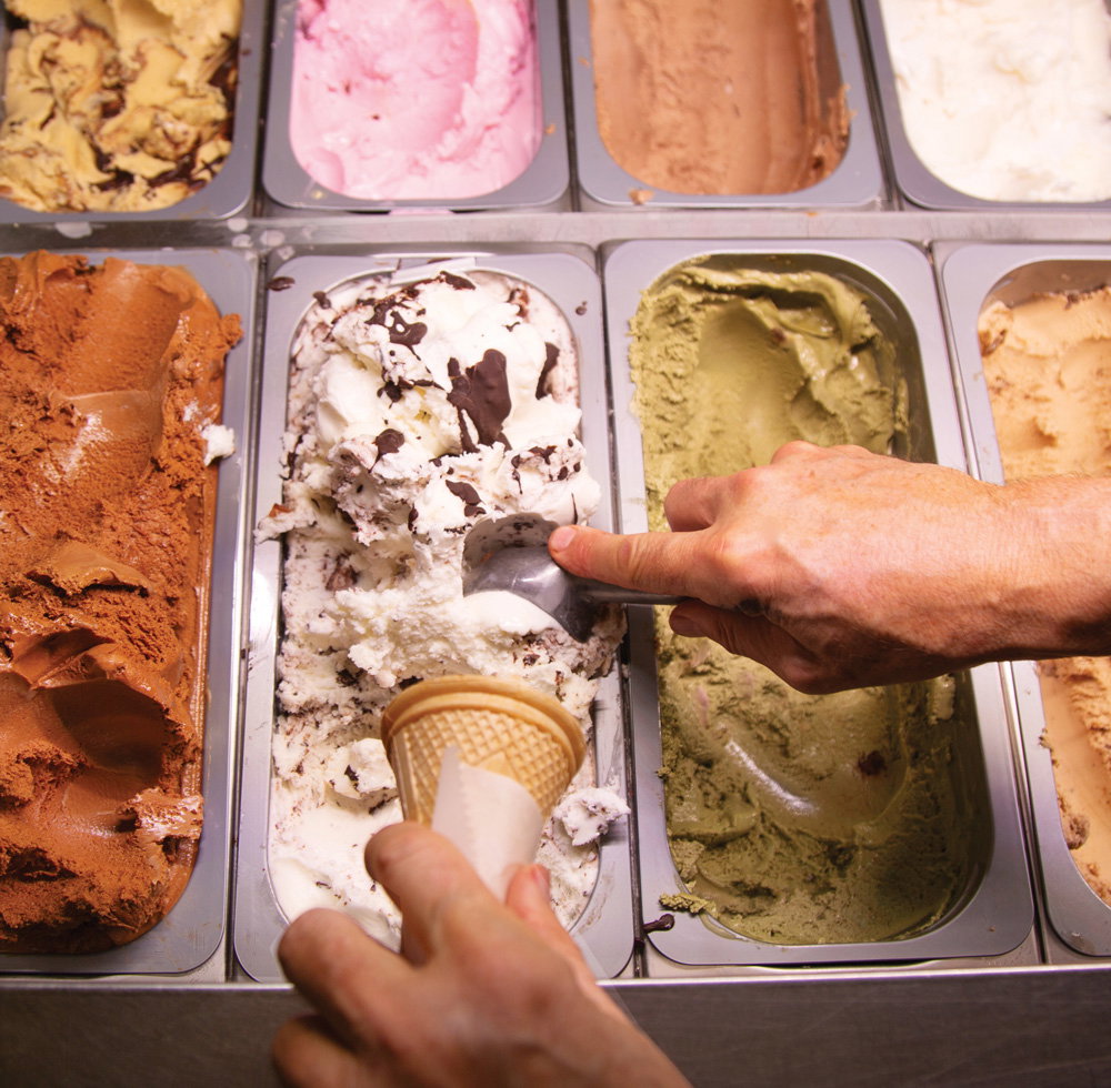 A hand scoops gelato on a cone