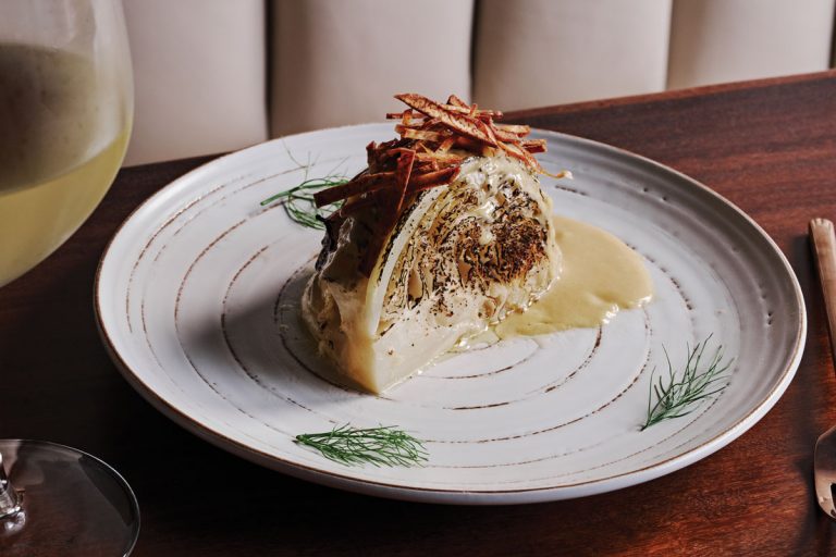 A half cut piece of cabbage with a glass of white wine next to it