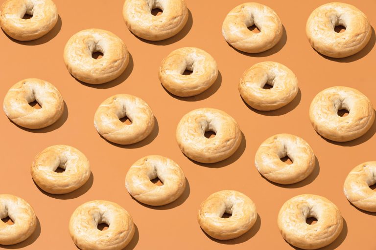 bagels are neatly lined up against a tan orange backdrop
