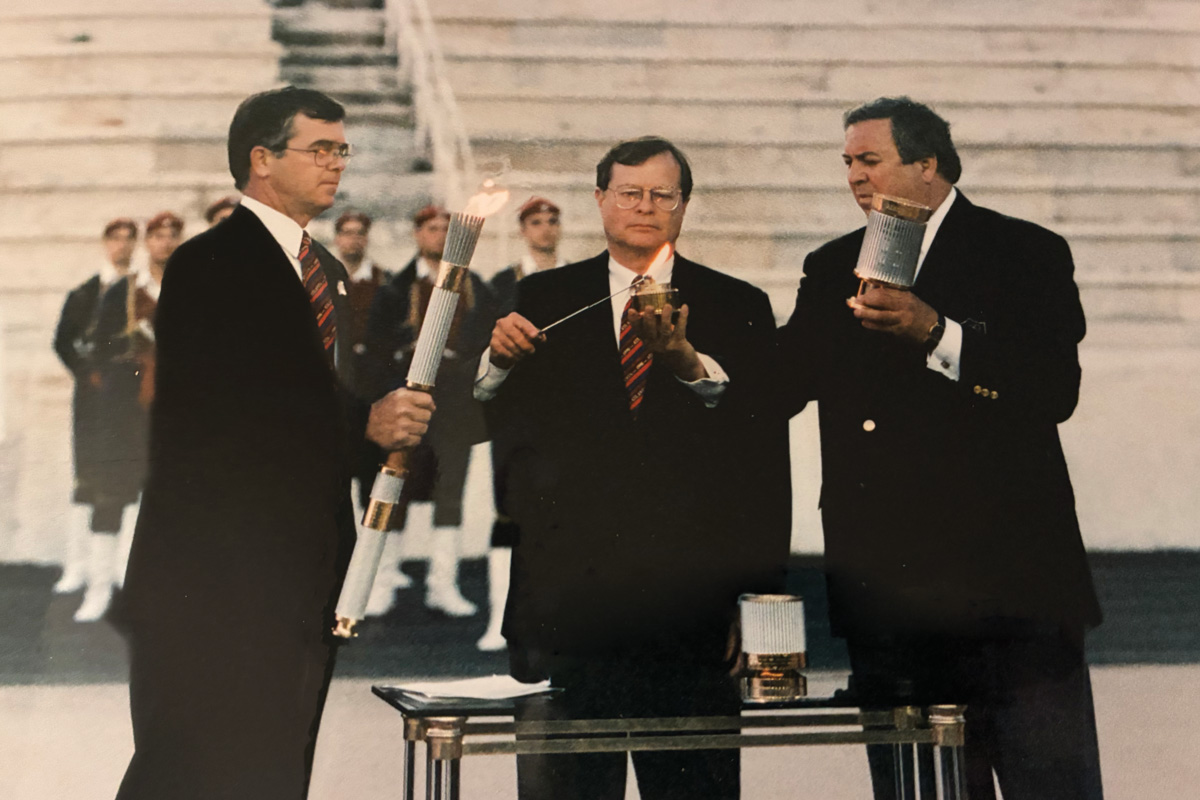 Billy Payne, Charlie Battle, and a Hellenic Olympic Committee representative transfer the Olympic flame in Athens, Greece, in 1996