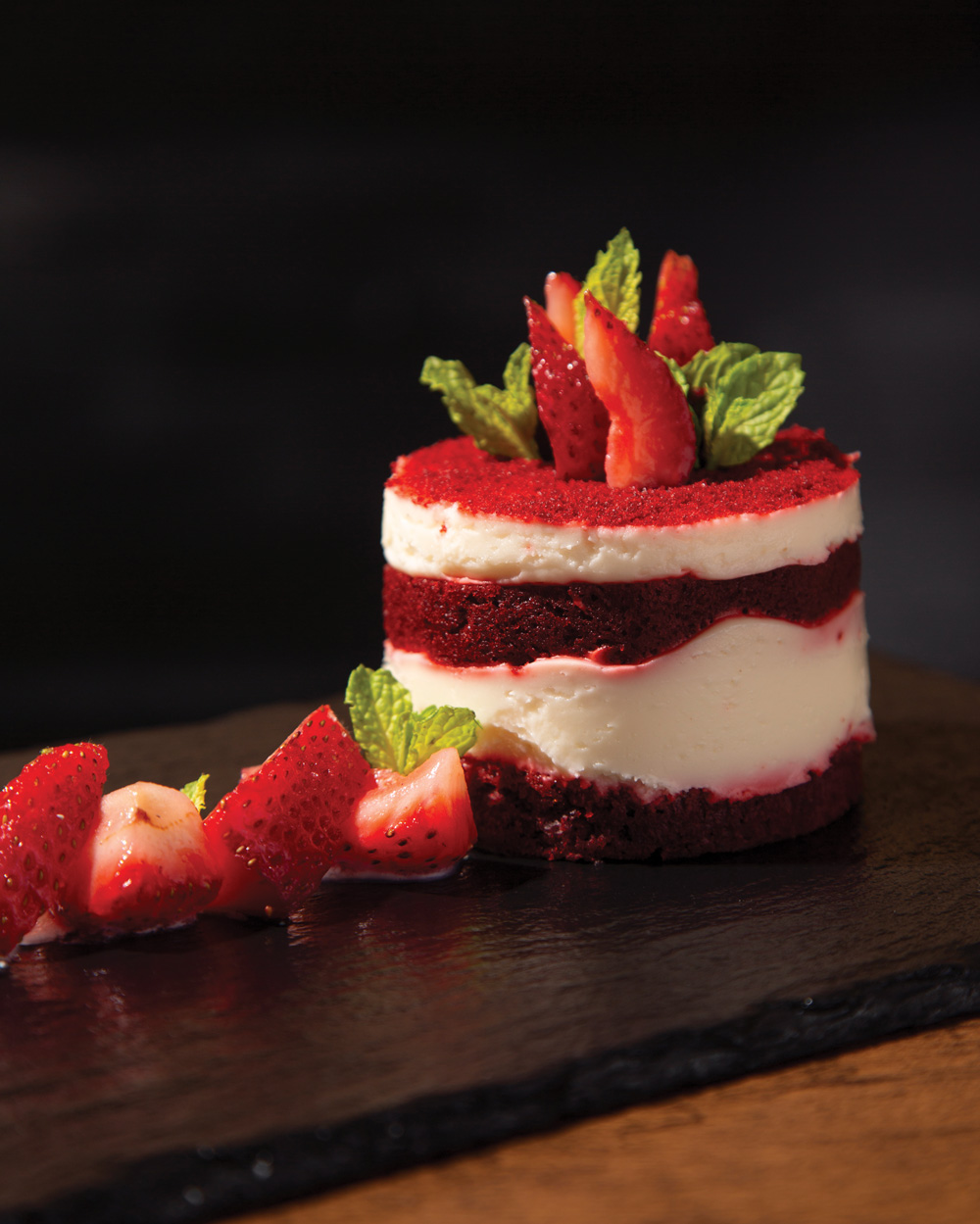 Red-velvet cake with strawberries on the left and atop