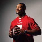 Bijan Robinson wears his red Falcons jersey while holding a football against a gradient black and white backdrop