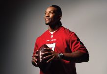 Bijan Robinson wears his red Falcons jersey while holding a football against a gradient black and white backdrop