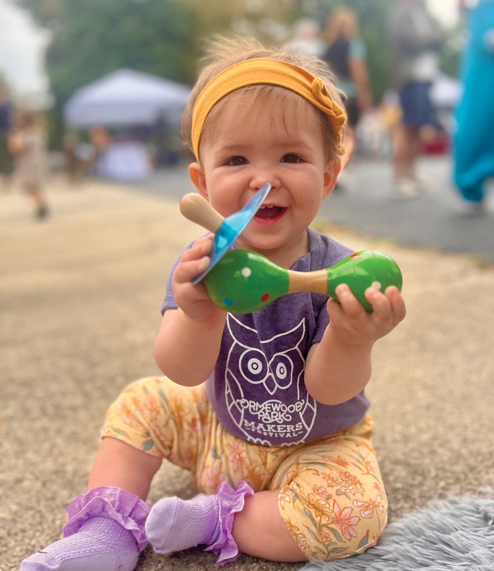 A baby smiles while attending th Ormewood Park Makers Festival