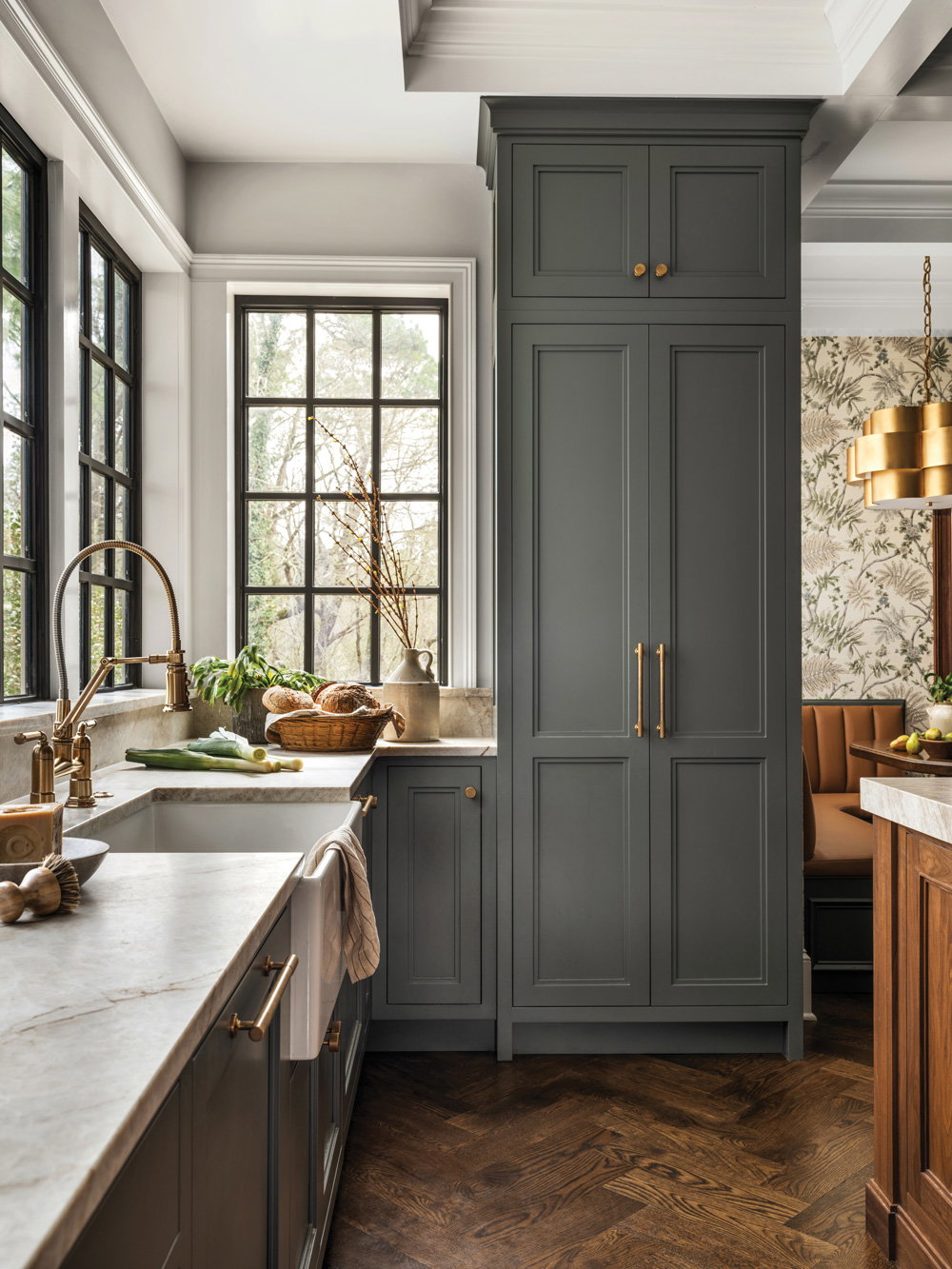 a rustic kitchen with green/grey colored cabinets with golden accents
