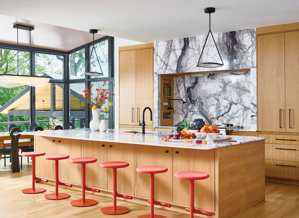 a cheerful kitchen with oak wooden cabinets and red/orange barstools
