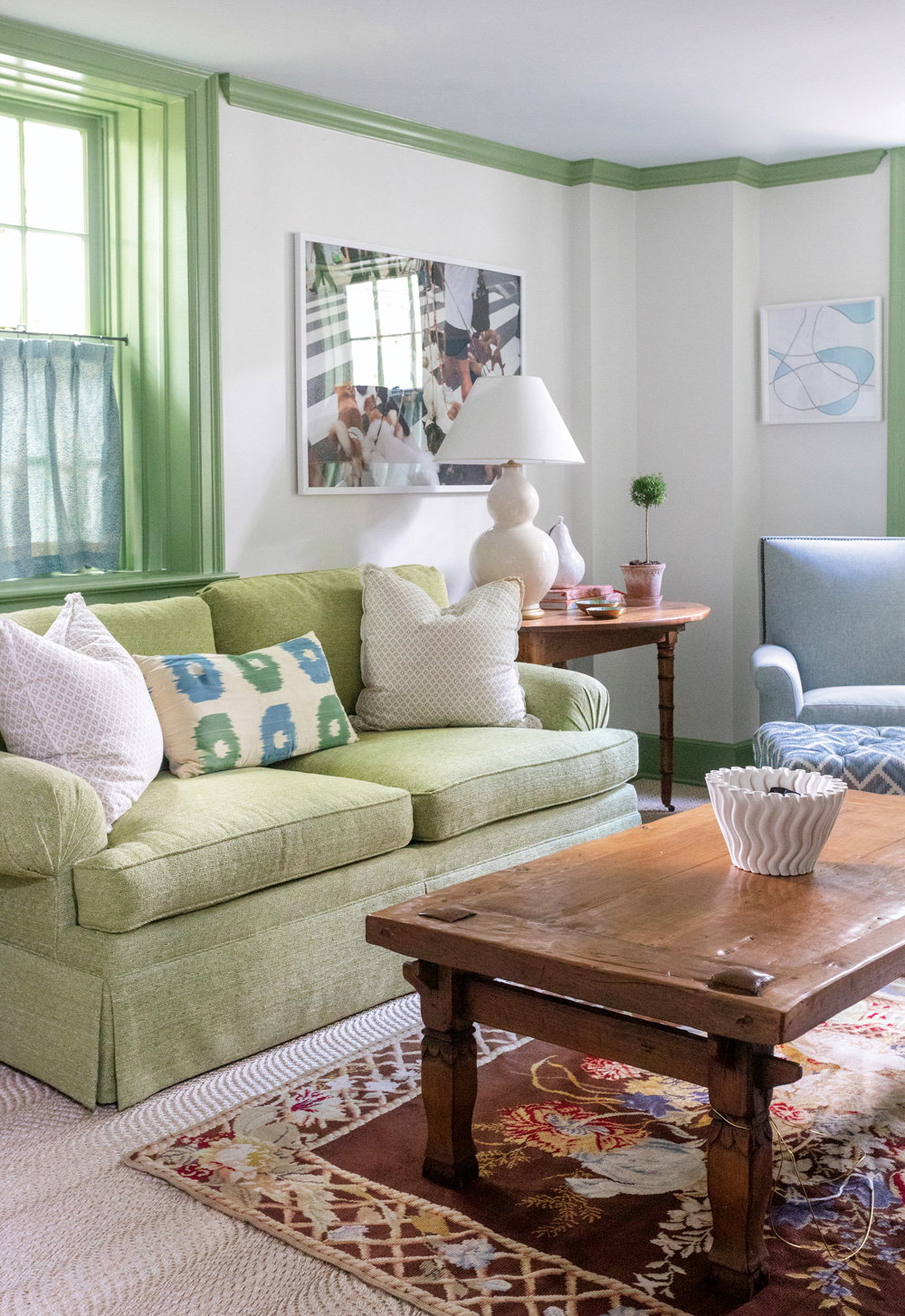a white walled living room with green crown molding and trims, and a matching green couch