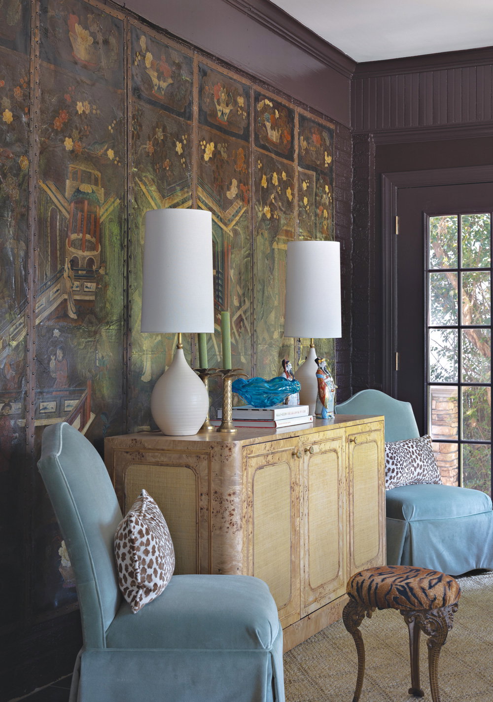 two light blue chairs and a console table with two tall beige lamps atop it
