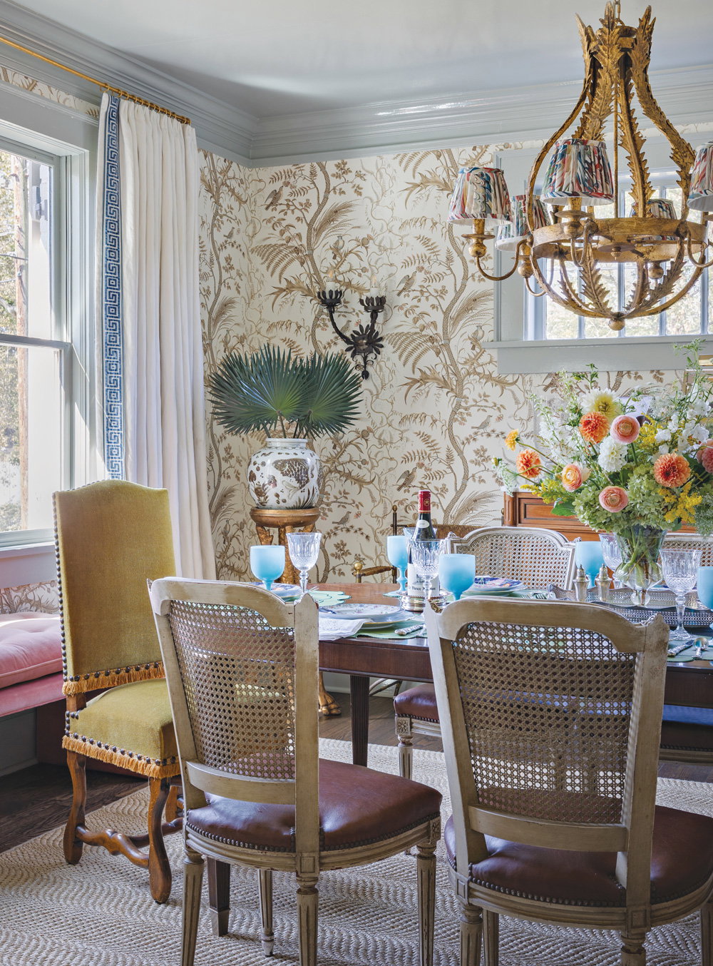 The dining room with white and gold wallpaper and a coordinating light blue, high-gloss paint on the ceiling and trim. An antique table and dining chairs as furniture