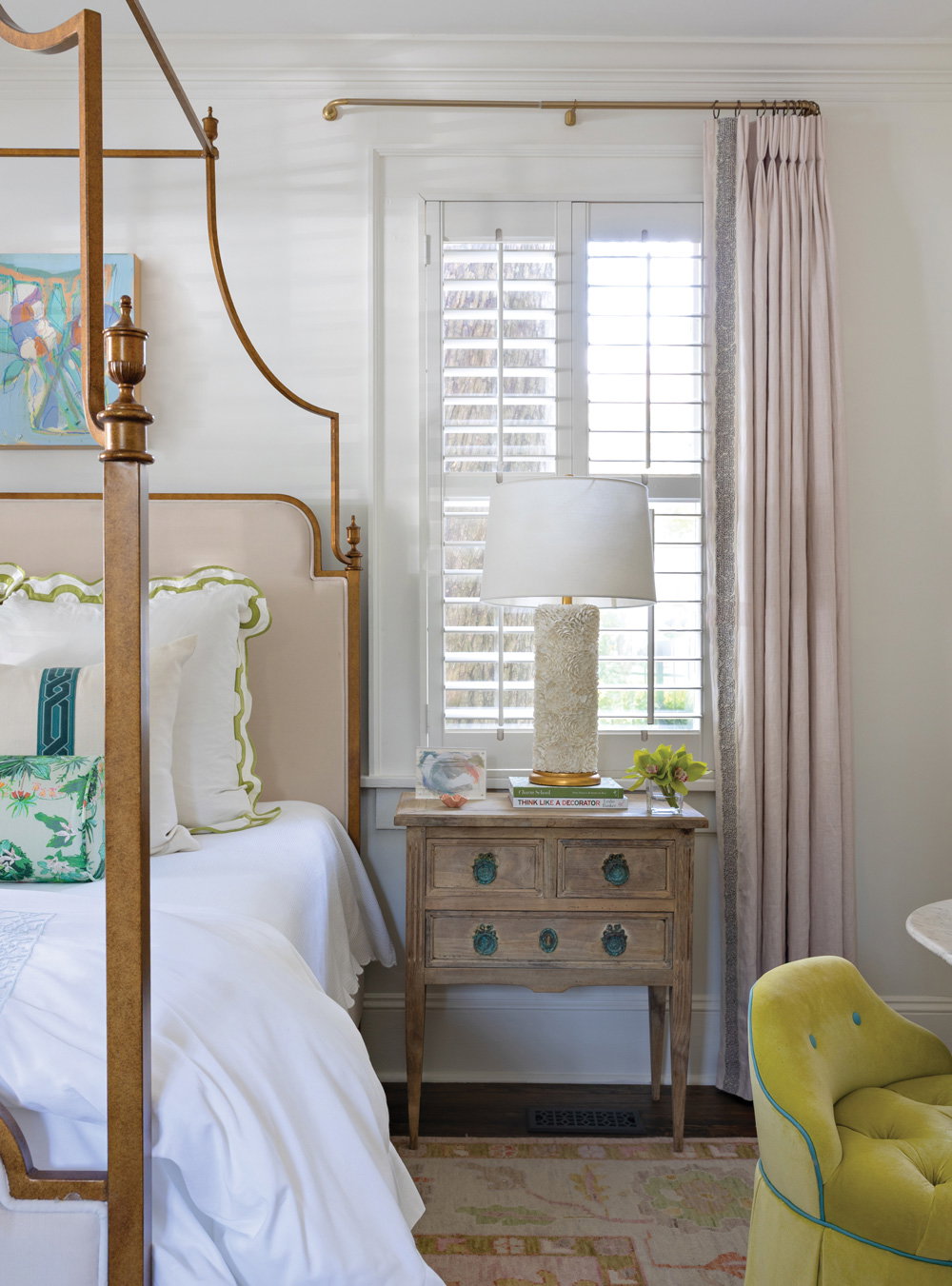 A canopy bed, crisp white bedding, and subtle pink accents in the guest bedroom