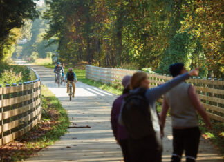 6 Atlanta Neighborhoods Where Community is Key: Smyrna Three people point and look at the trees while two bike riders ride down the Silver Comet Trail