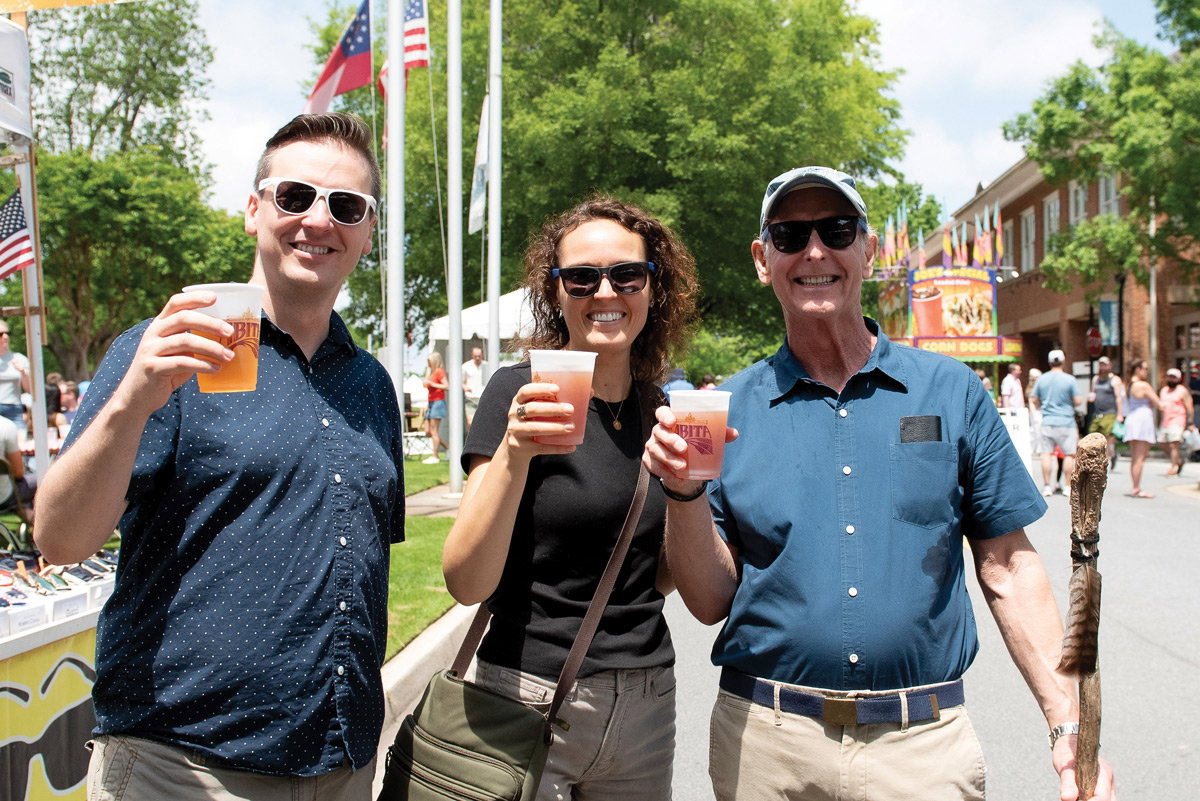 Three people hold drinks and smile while at the Jonquil Festival