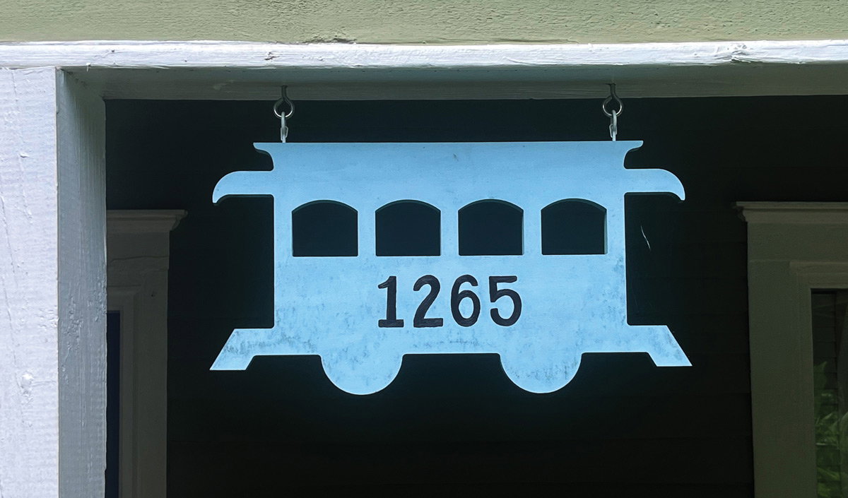 A blue train wood sign hanging in a front porch