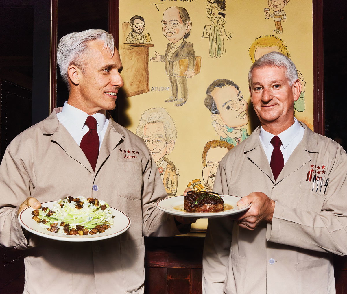 A server, Aaron, and John Wenger smile and hold plates of food