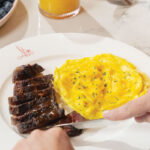 A man cuts into his steak and eggs at Brasserie Margot