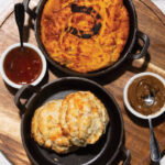 Down-home fare comes to Dunwoody Village at Stable Comfort Food and Cocktails biscuts, gravy, and an array of other dishes over a white brick table